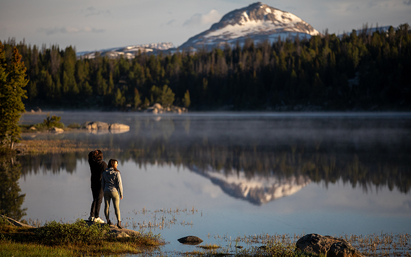 Two people at the edge of a lake. 