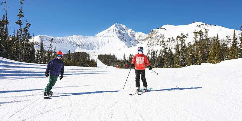 Two people skiing and snowboarding at Big Sky Resort