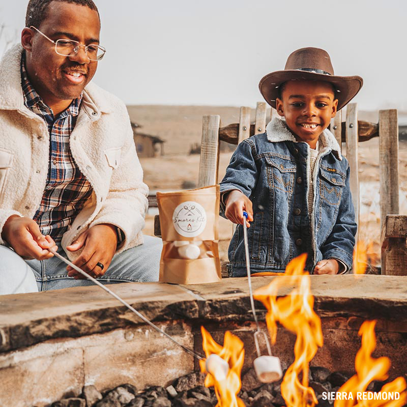 Father and son roasting s'mores over a campfire. 