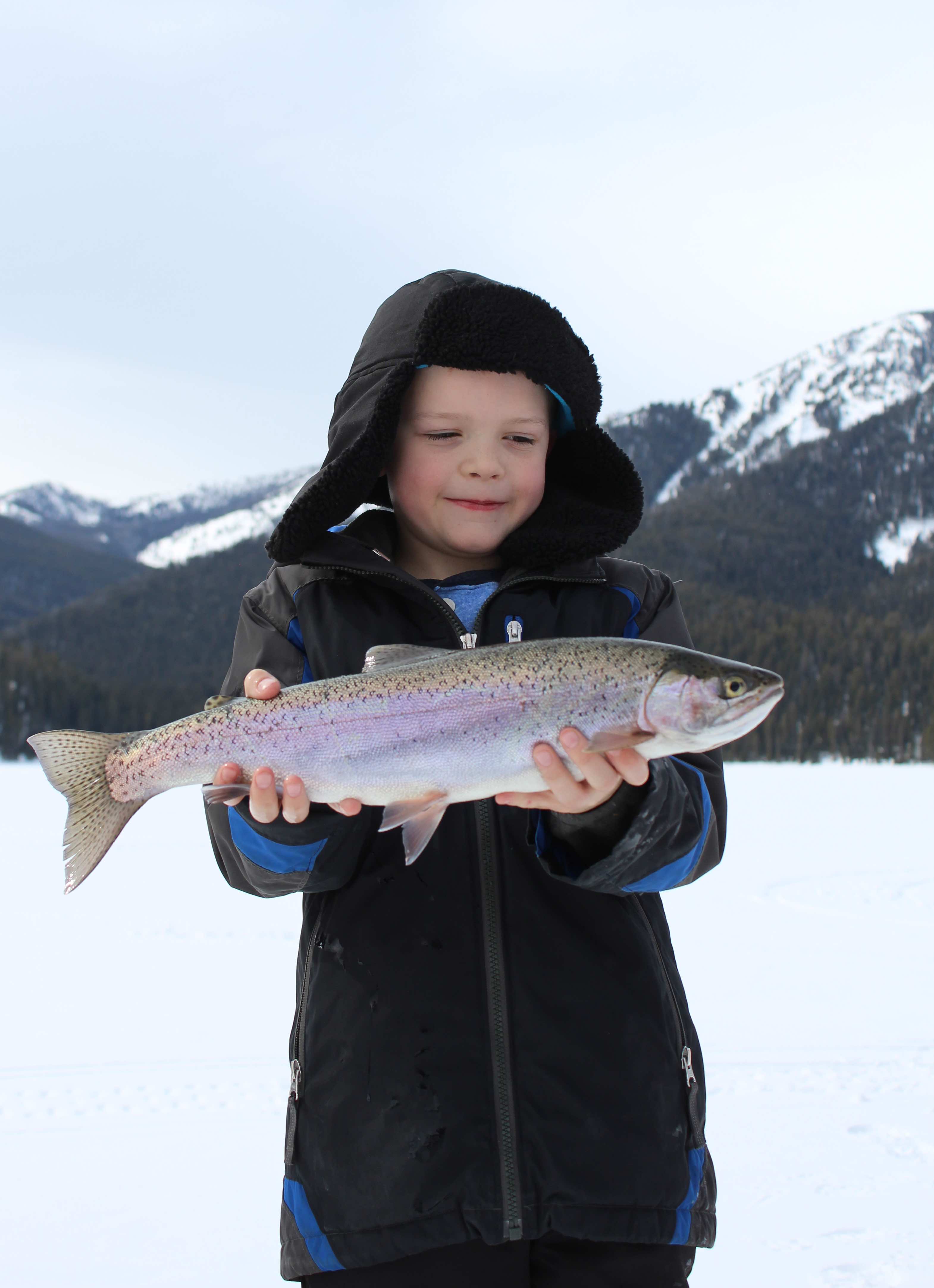 A boy holds up his catch of the day ice fishing in Yellowstone Country Montana near Yellowstone National Park