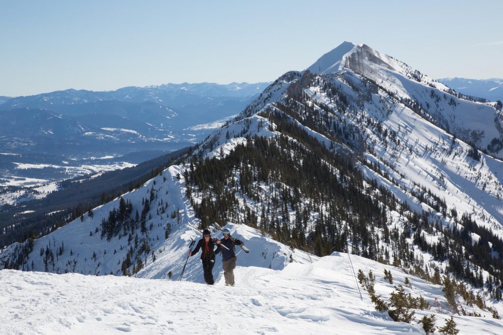 skiiers hike the ridge looking for fresh powder in montana