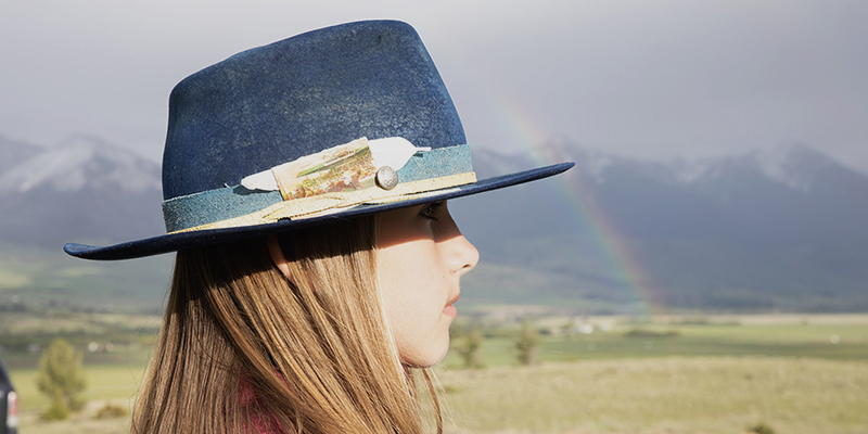 Young girl with cowboy hat and rainbow, Livingston, Montana