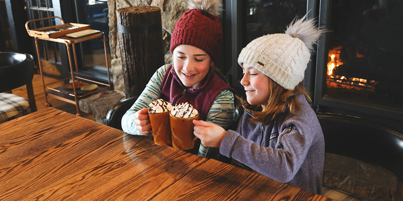 Two girls drinking hot cocoa at Lone Mountain Ranch in Big Sky, Montana