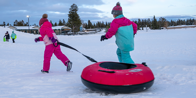 Two girls sledding at West Yellowstone's Kids N Snow. 